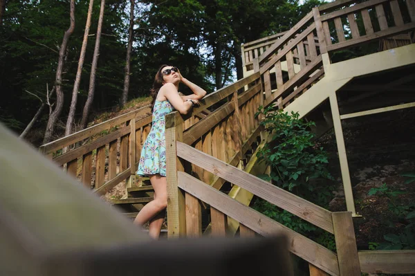 Park ve gülümseyen ahşap merdivenlerde oturan kız — Stok fotoğraf