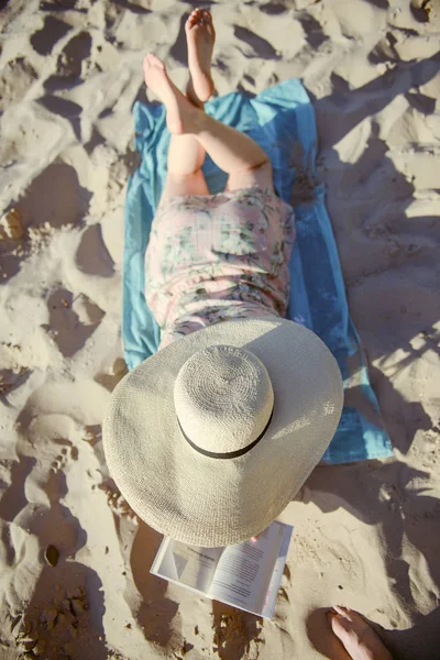 Porträt einer jungen Brünetten, die sich am Strand entspannt und ein Buch liest — Stockfoto
