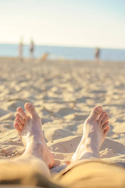 Kaki menutup di pantai di sunbed menikmati matahari pada hari musim panas yang cerah . — Stok Foto