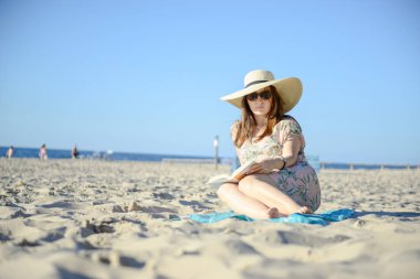 Genç esmer sahilde, bir kitap okumak rahatlatıcı bir portresi. Yaz saati