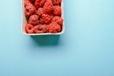 mavi bir arka plan üzerinde taze ahududu kutu