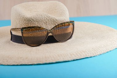 Hasır şapka ve güneş gözlüğü mavi zemin üzerine. plaj donanımları.