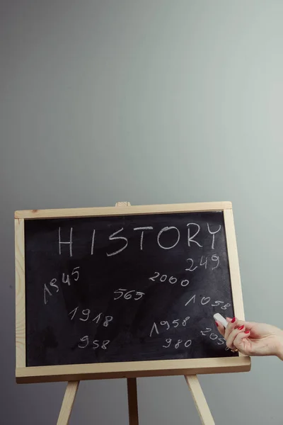 History, written with white chalk on a blackboard. Gray background