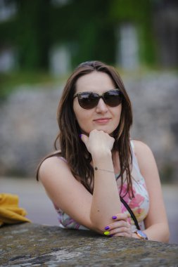 Güzel esmer, genç bir kadın elbise giyiyor ve sokakta yürüyor.