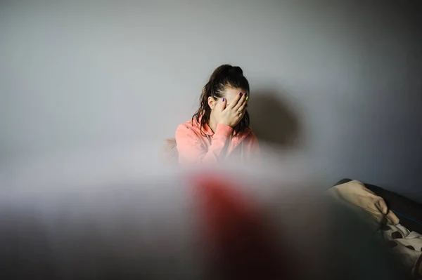 Woman sitting on her bed with some annoyed things and scratching her head — Stock Photo, Image