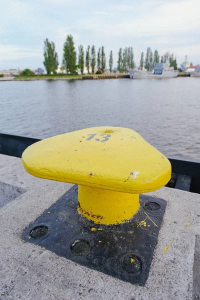 Vertically oriented picture of port pier with yellow mooring bollard — Stock Photo, Image