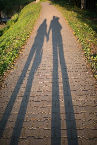 Spaziergänger und Schatten auf dem Bürgersteig, Kopfsteinpflaster auf dem Bürgersteig — Stockfoto