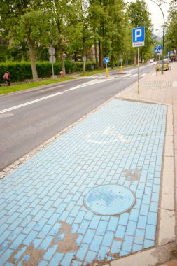 Park yeri üzerinde parlak mavi boyalı uluslararası Özürlüler sembolü