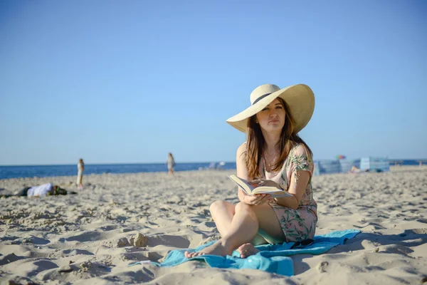 Ritratto di una giovane bruna che si rilassa sulla spiaggia, leggendo un libro — Foto Stock