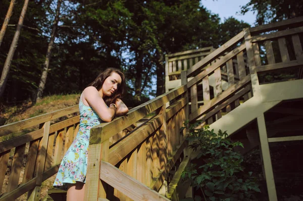 Menina sentada nas escadas de madeira no parque e sorrindo — Fotografia de Stock