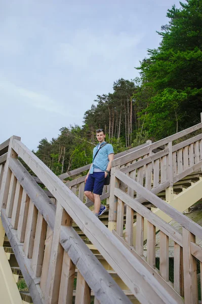 Hombre sentado en las escaleras de madera en el parque y sonriendo —  Fotos de Stock
