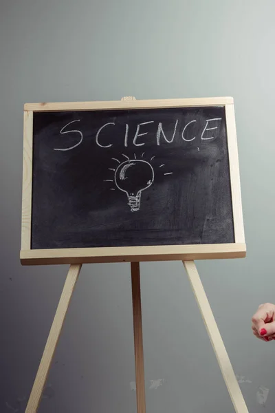 A teacher writing science, drawing chemistry elements on dark chalkboard by hand