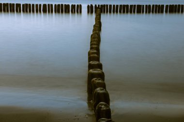 Baltık Denizi'nde gün batımında ahşap dalgakıran