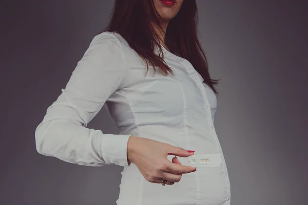 Junge Frau überprüft Schwangerschaftstest mit positivem Ergebnis. Studio — Stockfoto