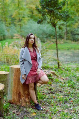 Altın sonbaharda parkta bir ağacın yanında duran kadın.