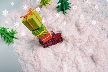 Oyuncak bir araba karda Noel ağacının altında hediyeler taşır. Yukarıdan bak. Boşluğu kopyala.
