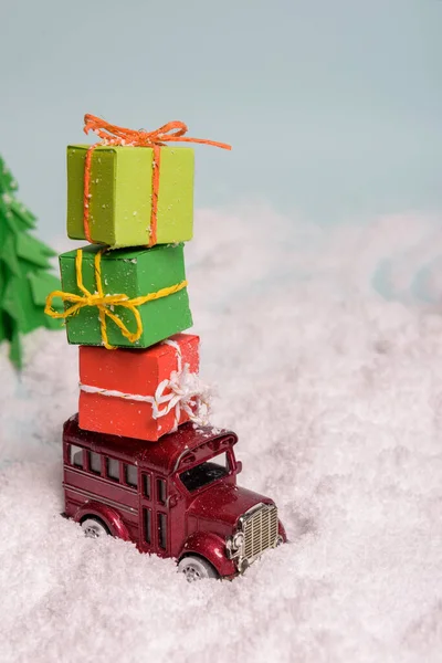 Zabawkowy samochód niesie prezenty pod choinką na śniegu. widok z góry. przestrzeń kopiowania. — Zdjęcie stockowe