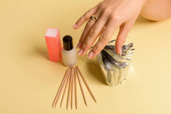The procedure for removing varnish from nails hybrid nails in progress. Gel nail polish remover foils on woman\'s hands.