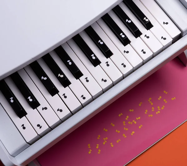 Witte speelgoedpiano met papieren notities. muziek piano concept. zicht van bovenaf — Stockfoto