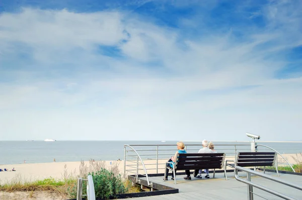 Turistas sentar em um banco na praia — Fotografia de Stock