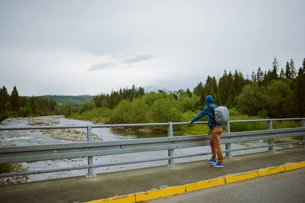 Turista maschio in piedi accanto al fiume di montagna — Foto Stock