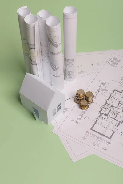 Witte familie papieren huis, stapel geld munten, huis projecten plan en blauwdrukken op munt achtergrond papier. Minimalistisch en eenvoudig concept, stijl. Verticale oriëntatie. — Stockfoto