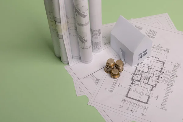 Casa de papel de familia blanca, pila de monedas de dinero, plan de proyectos de casa y planos en papel de fondo de menta. Concepto minimalista y simple, estilo. Orientación vertical . Imágenes de stock libres de derechos