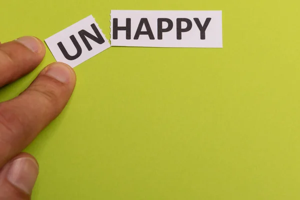 Man hand hålla kort med text olycklig, skära ordet "un" så det skrev "glad". Uppfattat utrymme. Limebakgrund. Studiosession — Stockfoto