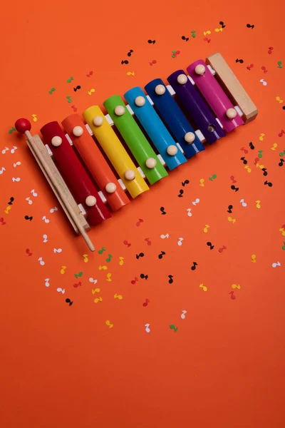 Trä xylofon i regnbågens färger för barn en isolerad på orange. Papper färgglada noter omger — Stockfoto