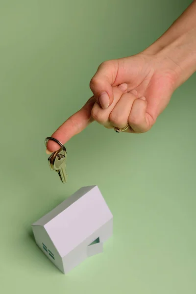 Weißes Familienpapierhaus. Hausschlüssel in der Hand auf mintfarbenem Hintergrund — Stockfoto