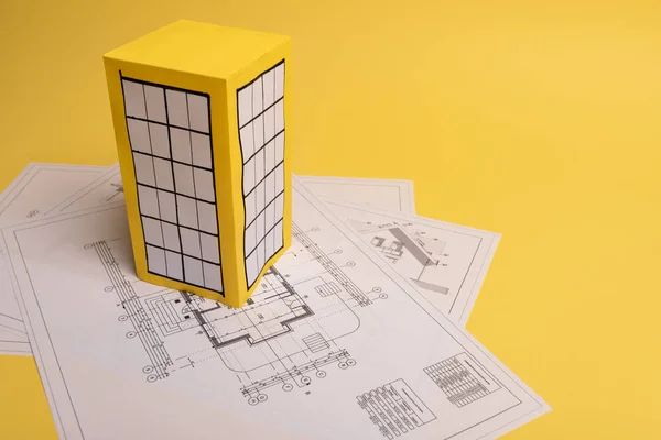 Bílý rodinný papírový dům nad bloky bytů na žlutém podkladovém papíru. Minimalistický a jednoduchý koncept, styl. Rozumím. Svislá orientace. — Stock fotografie