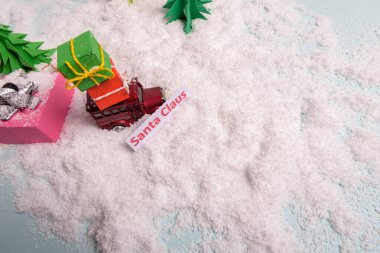 Oyuncak bir araba karda Noel ağacının altında hediyeler taşır. vie