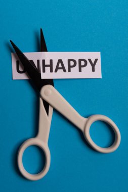 Kart esprili mesaj mutsuz, 'un' sözcüğünü keserek 'mutlu' yazmış. Uzayı kopyala Mavi arka plan. Stüdyo çekimi