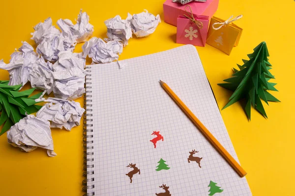 Caja de regalo y árboles de origami de papel verde con bloc de notas en el escritorio amarillo, mesa. Navidad para hacer lista de texto —  Fotos de Stock
