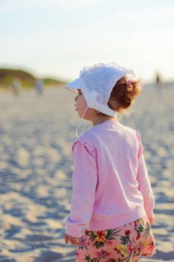 Güneşli bir kumsalda küçük sevimli bir kız. Otantik çocukluk görüntüsü.