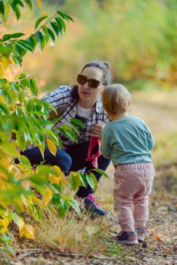 Parktaki mutlu anne ve kız. Aile hayatı olan güzel doğa manzarası. Mutlu aile yeşil çimlerin üzerinde birlikte dinleniyor, otantik yaşam tarzı görüntüsü.