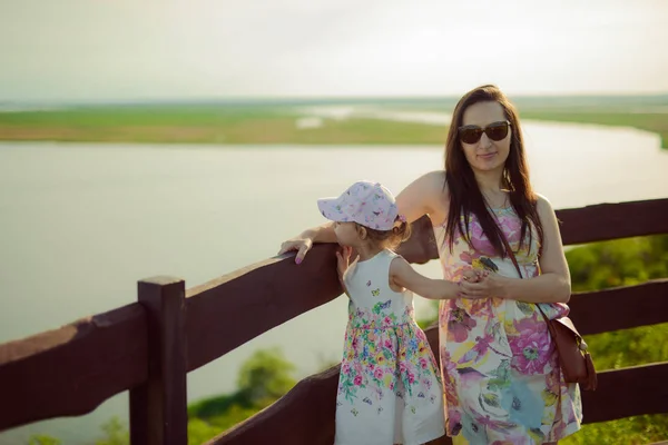 Mãe e filha felizes no parque. Cena da natureza da beleza com estilo de vida familiar ao ar livre. Família feliz descansando juntos na grama verde, imagem de estilo de vida autêntica . — Fotografia de Stock