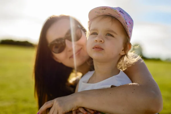 Madre e figlia felici nel parco. Scena di bellezza natura con stile di vita familiare all'aperto. Famiglia felice che riposa insieme sull'erba verde, autentica immagine di stile di vita . — Foto Stock