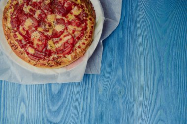 Masada ev yapımı pepperoni pizza. Domates, peynir ve jambon.