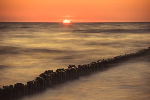 Wellenbrecher aus Holz bei Sonnenuntergang an der Ostsee — Stockfoto