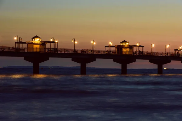 Ostsee bei schönem Sonnenuntergang am Strand von Miedzyzdroje. Die polnische Ostseeküste. berühmte Stadt unter den Touristen. Anlegestelle bei Sonnenuntergang — Stockfoto