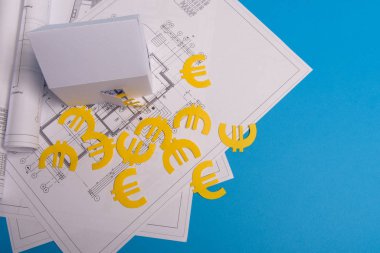 Kağıt gökdelenler, avro parası, ev projeleri planı ve mavi arkaplan kağıdındaki planlar. Minimalist ve basit bir kavram, tarz. Yatay oryantasyon. Yukarıdan görüntüle