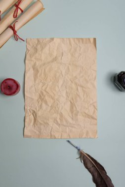 Kuzgun tüyü, mürekkep hokkası ve kırmızı arka planda eski sarı kağıt. Boşluğu kopyala.