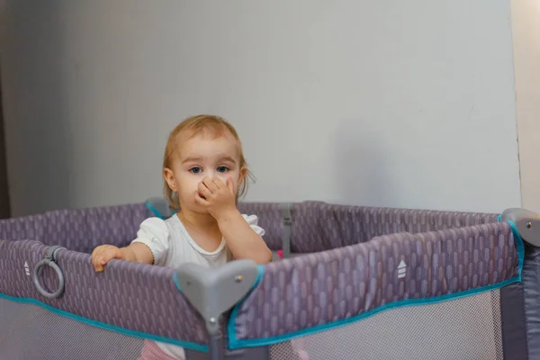 小宝宝在一个小床上。 人物形象小孩近身。 18个月大的女婴站在婴儿床里 — 图库照片