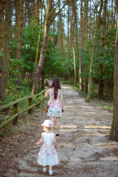 Mãe e filha felizes no parque. Cena da natureza da beleza com estilo de vida familiar ao ar livre. Família feliz descansando juntos na grama verde, se divertindo ao ar livre. Felicidade e harmonia na vida familiar — Fotografia de Stock