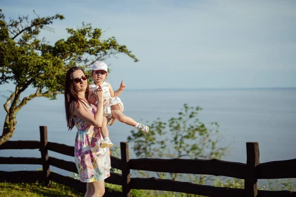 Mãe e filha felizes no parque. Cena da natureza da beleza com estilo de vida familiar ao ar livre. Família feliz descansando juntos na grama verde, se divertindo ao ar livre. Felicidade e harmonia na vida familiar — Fotografia de Stock