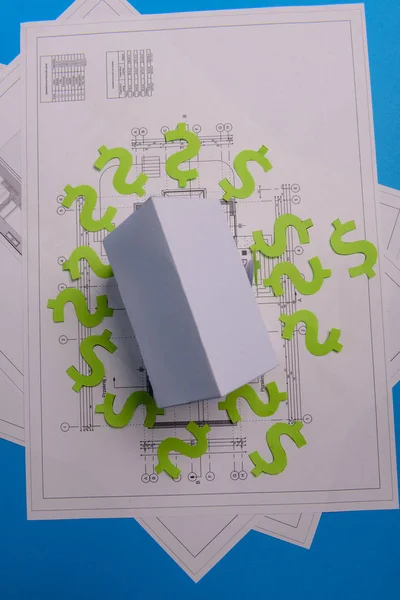 紙の高層ビル、私たちのドルのお金、家のプロジェクト計画と青い背景の紙の設計図。ミニマルでシンプルなコンセプト、スタイル。水平方向。上からの眺め。スペースのコピー. — ストック写真