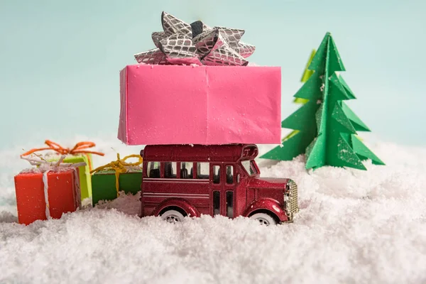 Игрушечный автомобиль несет подарки под елкой на снегу. vie — стоковое фото