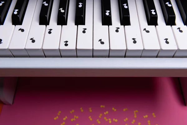 कागदाच्या नोट्ससह पांढरा टॉय पियानो. संगीत पियानो संकल्पना. वरील दृश्य — स्टॉक फोटो, इमेज