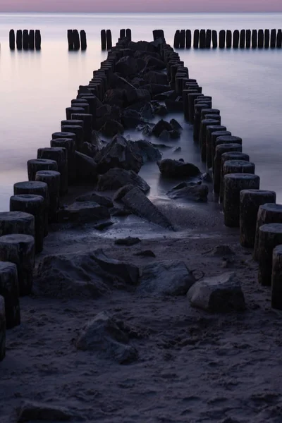 Quebra-mar de madeira ao pôr do sol no mar Báltico — Fotografia de Stock